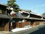 Two storied traditional Japanese houses next to a street.