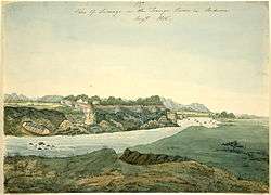 Watercolour of a river and a fort. The river's flow is disturbed by some small rocks; a hidden creek or stream runs into the river in the foreground; a small boat has been pulled out of the water and left resting on the far bank. The fort, with six visible turrets, is built on the edge of a cliff overlooking the river. Hills line the distant background.