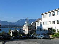 Typical Kitsilano street showing parked automobiles, multi-unit housing, mountains in background.