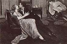 Violet Kemble-Cooper and John Barrymore half-sitting, half-lying in an eager embrace on a couch, about to kiss