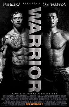 Two shirtless, muscled men stand against a black background. The word "Warrior" is written sideways between them.