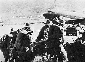 Soldiers in slouch hats manhandle an artillery piece from a plane