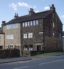 three storey stone built, end of terrace cottage with six windows on the floor under the roof