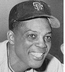 Black-and-white photo of Willie Mays, smiling in a San Francisco Giants hat